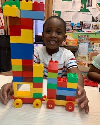 A preschooler proudly showing his block tower