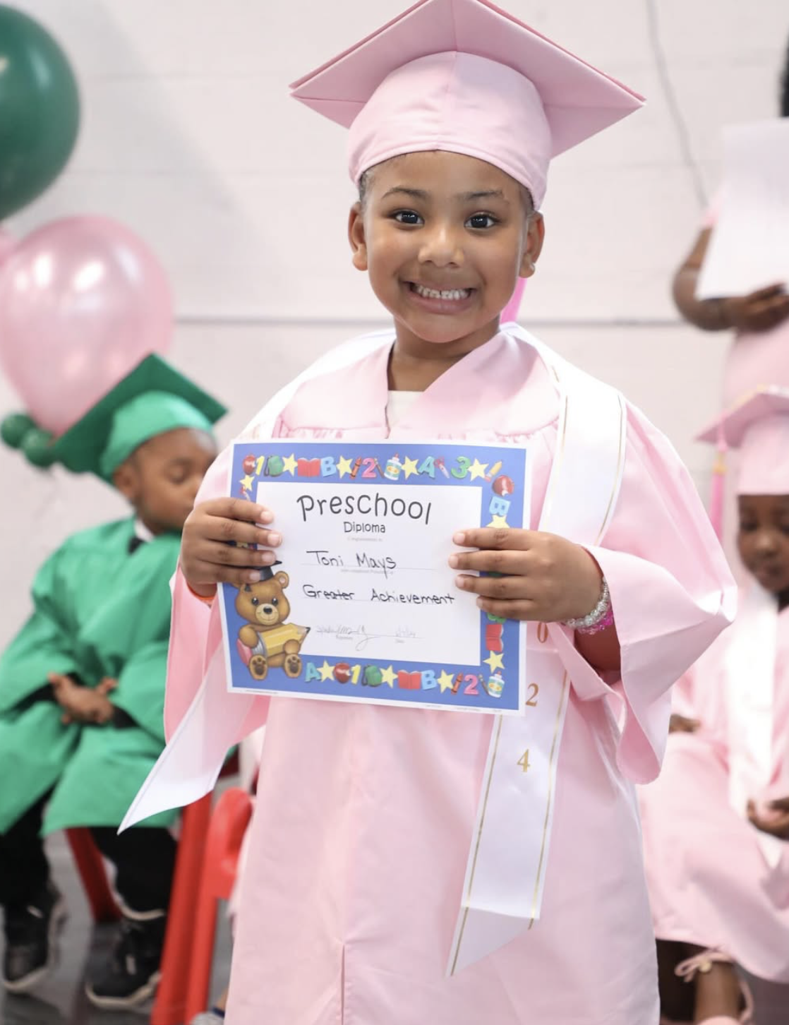 A proud preschool graduate holding her diploma